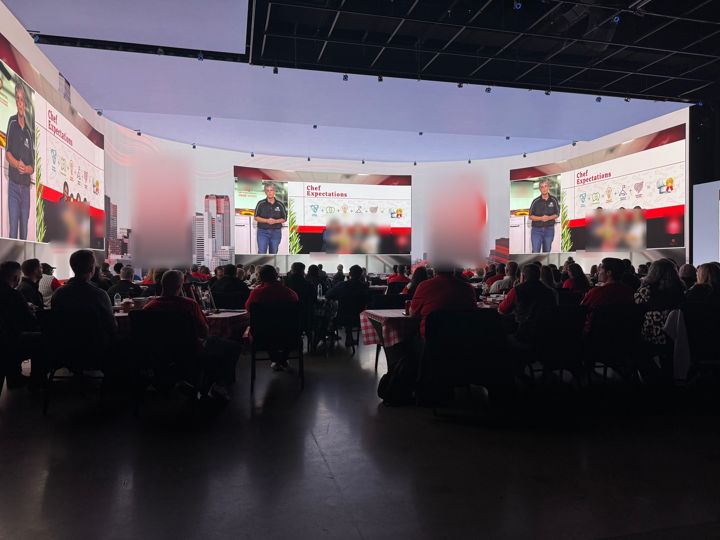 Leadership forum audience facing large immersive presentation screens